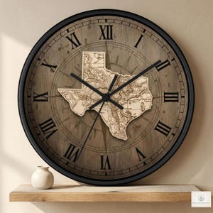 May include: A round wall clock with a black frame and a wooden face. The clock face features a map of Texas in the center, surrounded by Roman numerals and a compass design. The clock hands are black.