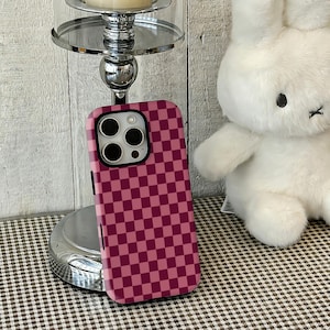 Pink Red Checkers Sweet Phone Case—a "strawberry milk" for girls. Inspired by sweet strawberry desserts, this case cleverly combines soft "Pink" with vibrant "Red" checkers, instantly filling the atmosphere with sweet "Girly" vibes. This design with a built-in soft light filter offers both retro playfulness and an energetic vibe that lifts your mood. It fits iPhone and Samsung series perfectly, making it an excellent accessory for creating date sweet-style or Japanese girl outfits.