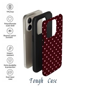 Puede incluir: Funda de tel&eacute;fono multicapa con una cubierta burdeos con un patr&oacute;n de peque&ntilde;os corazones rosas. La funda incluye un forro de TPU, una carcasa exterior de policarbonato y es resistente a los impactos. Se muestra el texto "Tough Case".