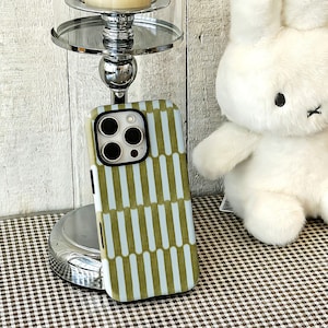May include: A rectangular phone case featuring a repeating pattern of vertical olive green bars separated by light blue stripes. The case has a black camera cutout frame with three circular lens openings and a flash sensor on the upper left corner.
