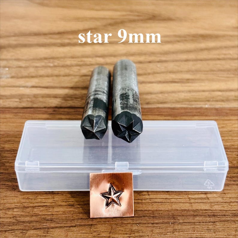 May include: Two metal star-shaped stamps, 9mm, with a clear plastic case and a stamped copper square. The stamps are cylindrical with a star design on the bottom. The text "star 9mm" is above the stamps.