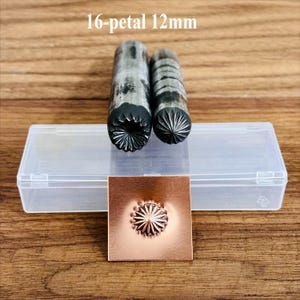 May include: Two metal stamping tools with a 16-petal design, 12mm in size, are displayed next to a copper square with an embossed flower. The tools and copper square are on a wooden surface. The text "16-petal 12mm" is above the tools.