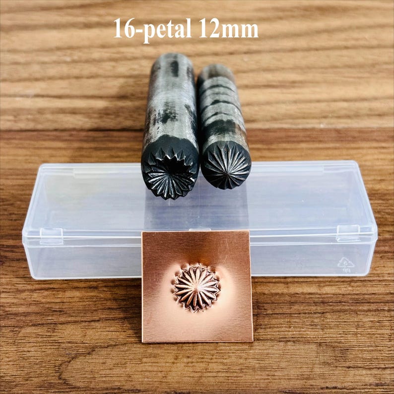 May include: Two metal stamping tools with a 16-petal design, 12mm in size, are displayed next to a copper square with an embossed flower. The tools and copper square are on a wooden surface. The text "16-petal 12mm" is above the tools.