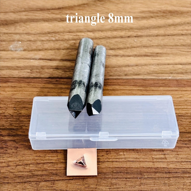 May include: Two metal triangle punches with 8mm tips and a clear plastic case. A small copper square with a triangle shape is also visible. The text "triangle 8mm" is at the top of the image.
