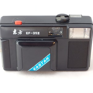 May include: Black EF-35II camera with a red shutter button and a flash. The camera has the text "东方" and "EASTAR" on it. The camera is rectangular and has a textured grip.