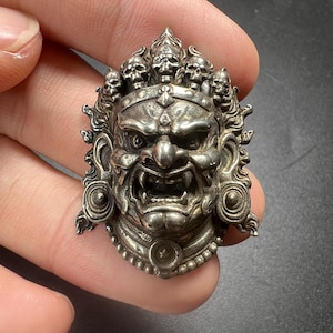 Colgante vintage artesanal de cobre blanco Lima con el rostro de Mahakala, amuleto protector budista tibetano de carácter iracundo.