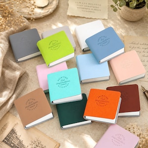 May include: A collection of small square notebooks in various colours including lime green, light blue, pink, orange, dark green, brown, white, and grey. Each notebook cover features the embossed text Painting Art inspiration NOTEBOOK.