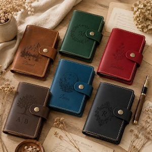 Peut inclure: Six carnets rectangulaires en cuir avec fermetures à pression, chacun présentant des motifs gravés au laser et des noms uniques : Daniel, M, Isabella, Lucas, AB et R. Les carnets sont marron, vert, rouge, bleu, brun foncé et noir.