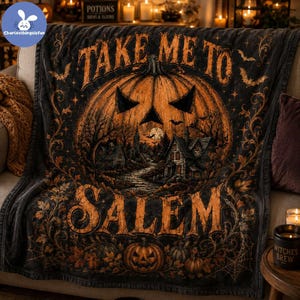 May include: A black and orange fleece throw blanket featuring a large jack-o'-lantern with a spooky house scene inside, surrounded by bats and vines. The text "TAKE ME TO SALEM" is printed in large, bold orange letters across the top and bottom.