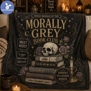 May include: A black throw blanket featuring the text PROUD MEMBER OF THE MORALLY GREY BOOK CLUB, a human skull resting on a stack of books, roses, and a lit candle. The design includes the phrases MEET WEEKLY, TRIGGER WARNINGS WELCOME, and ENEMIES TO LOVERS MONTH.