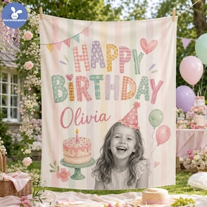 May include: A rectangular fabric backdrop featuring pastel vertical stripes, a colorful Happy Birthday banner, a birthday cake illustration, and a photo of a smiling child wearing a party hat with the name Olivia printed in cursive script.