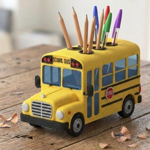 May include: A yellow school bus-shaped desk organizer with pencils and pens in the top holes. The bus has black wheels, windows, and details, with the word "SCHOOL BUS" on the front. A red stop sign is on the side.
