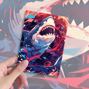 May include: A rectangular print featuring a stylized illustration of a shark with its mouth open, displaying sharp teeth. The artwork uses a vibrant color palette of deep blue, bright red, and white, with abstract geometric shapes and energetic brushstrokes.