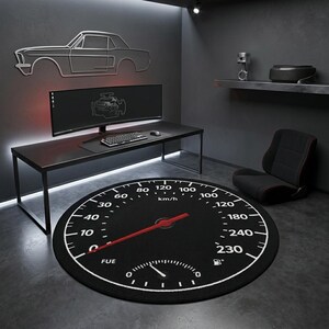 Puede incluir: Una alfombra redonda negra con diseño de velocímetro, con números blancos y una aguja roja que apunta a 160 km/h. La alfombra tiene un indicador de combustible y la palabra "FUE". Un escritorio negro, una computadora y arte mural con temática de automóviles completan la habitación.