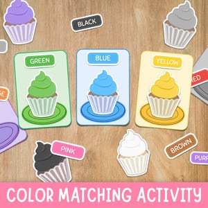 Puede incluir: Un juego de asociación de colores con tarjetas ilustradas de cupcakes verdes, azules y amarillos, junto con etiquetas individuales para negro, gris, blanco, naranja, rojo, marrón, rosa y morado, con el texto COLOR MATCHING ACTIVITY.