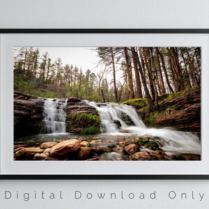 Può includere: Fotografia incorniciata di una cascata che scorre su rocce a strati. L'acqua scorre rapidamente, creando un effetto sfocato. L'area circostante presenta alberi e una foresta, con il testo "Digital Download Only" in basso.