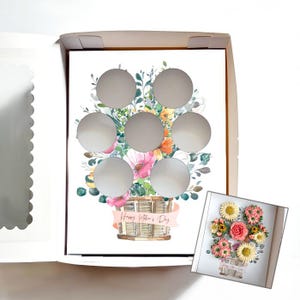 May include: A white box with a floral design for Mother's Day. The design features a basket of colorful flowers with six circular cutouts. The words "Happy Mother's Day" are on a banner across the basket. A smaller image of the floral arrangement is in the lower right corner.