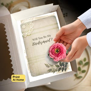 Puede incluir: Una tarjeta rectangular dentro de una caja abierta con el texto Will You Be My Bridesmaid? en letra cursiva marrón. La tarjeta tiene un fondo crema vintage con un detalle de encaje blanco, una ilustración de peonía rosa y hojas verdes.