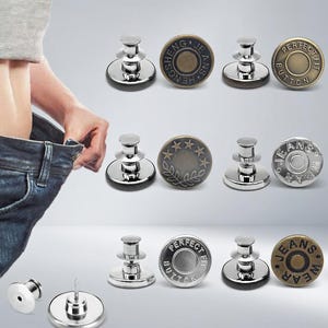 Könnte beinhalten: Eine Sammlung von silbernen und bronzefarbenen Jeansknöpfen mit verschiedenen Designs und Texten. Einige Knöpfe tragen die Aufschrift "SHENG JEANS", "PERFECT FIT BUTTON" und "JEANS WEAR". Die Knöpfe werden vor einem hellen Hintergrund gezeigt.