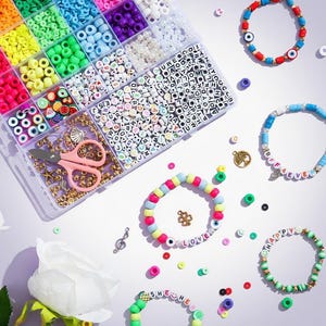 May include: A craft kit with a variety of colorful beads, scissors, and bracelets. The bracelets feature letter beads spelling out words like "LOVE" and "HAPPY". The beads are in various colors, including pink, green, blue, and yellow.