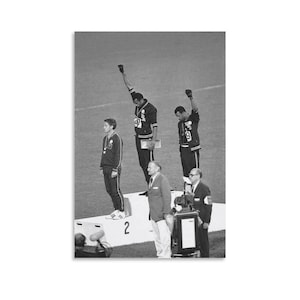 May include: Black and white photograph of the 1968 Olympics medal ceremony. Two athletes stand on the podium with raised fists, while another stands with a medal. Officials and a podium are also visible.