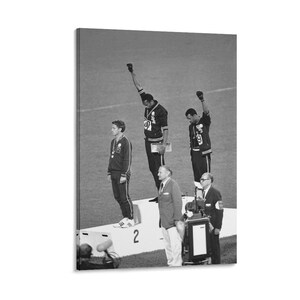 May include: Black and white photograph of the 1968 Olympics medal ceremony. Two athletes on the podium raise a black-gloved fist. A third athlete stands with a medal. Officials stand below the podium.