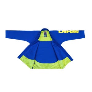 May include: A blue Jiu-Jitsu gi with yellow text that reads "DURINHO" across the shoulder. The inside lining is a bright green with a geometric pattern. The gi is spread out, showing the inside and the sleeves.