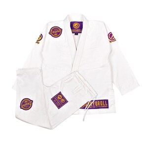 Puede incluir: Uniforme blanco de Jiu-Jitsu con parches bordados en morado y dorado. El uniforme incluye una chaqueta y un pantalón. Los parches presentan la marca "Shoyoroll" y "Jiu Jitsu". El uniforme está hecho de un material duradero.