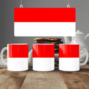 Puede incluir: Tres tazas de cerámica con un diseño bicolor horizontal que presenta una mitad superior de color rojo vibrante y una mitad inferior de color blanco. Las tazas están dispuestas en fila, mostrando el mismo patrón rojo y blanco.