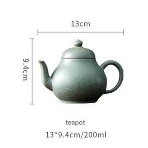 May include: A teal-colored ceramic teapot with a rounded body, a curved spout, and a loop handle. The teapot is 13 cm long and 9.4 cm high. The text "teapot" is below the teapot.