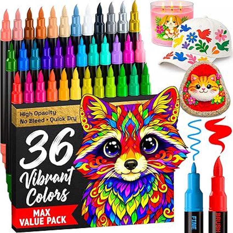 May include: A set of 36 vibrant color markers in a black box featuring a colorful raccoon illustration, text reading 36 Vibrant Colors, High Opacity, No Bleed, Quick Dry, Max Value Pack, a white baseball cap with floral patterns, and a painted cat rock.