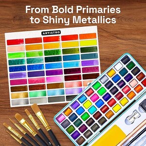 May include: A watercolor paint set in a light blue metal tin with numerous square pans of various colors, accompanied by a color swatch chart labeled ARTISTRO with the text From Bold Primaries to Shiny Metallics and five paint brushes.