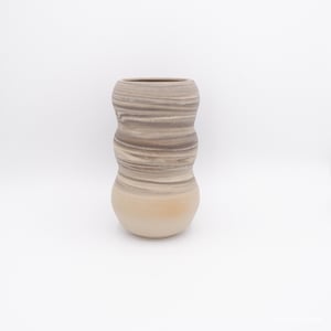 Op de afbeelding: Een handgemaakte keramische vaas met een unieke, golvende vorm. De vaas heeft een gemarmerd effect met beige, bruine en bruine tinten. De vaas is ongeveer 25 cm hoog, met een brede basis en een smallere opening.