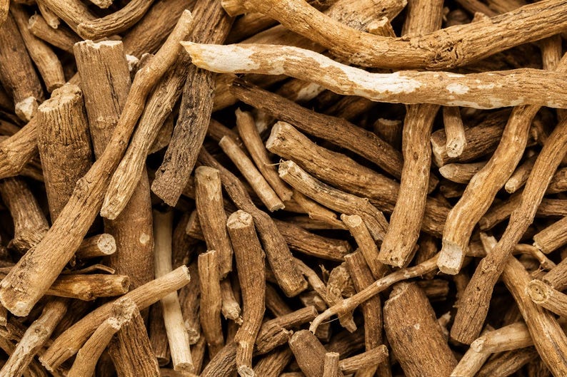 May include: A collection of dried, light brown woody roots arranged in a dense, overlapping pile. The roots vary in thickness and length, featuring a rough, fibrous texture with visible bark markings and irregular, jagged ends throughout the cluster.