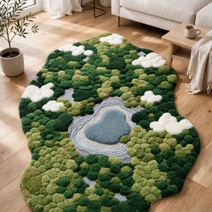 May include: An irregular shaped area rug featuring a textured, tufted landscape design. The rug displays shades of dark and light green representing forest foliage, a central blue pond with gray ripples, and fluffy white tufted clouds.