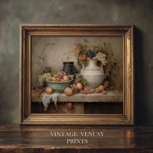 May include: A framed still life painting with a gold frame. The artwork shows a table with a bowl of peaches, grapes, and two vases. The text "VINTAGE VENUSY PRINTS" is at the bottom of the frame.