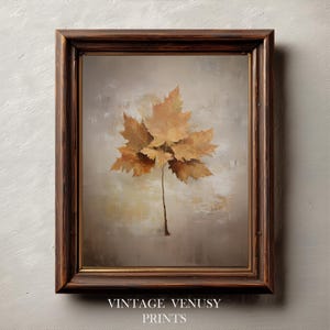 May include: A framed print featuring a cluster of dried maple leaves in shades of brown and gold. The leaves are arranged on a neutral, textured background. The frame is dark brown. The text "VINTAGE VENUSY PRINTS" is at the bottom.