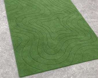 May include: A rectangular green rug with a topographic map design. The rug features a series of curved lines that create a three-dimensional effect. The rug is made of a soft, plush material and is a solid green color.