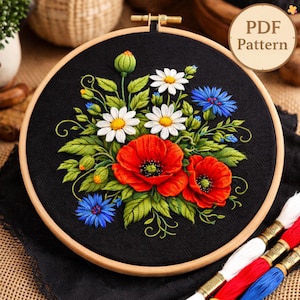 Puede incluir: Diseño floral bordado sobre tela negra, con amapolas rojas, margaritas blancas y acianos azules, en un bastidor de madera. El texto "PDF Pattern" es visible. Un proyecto de costura.