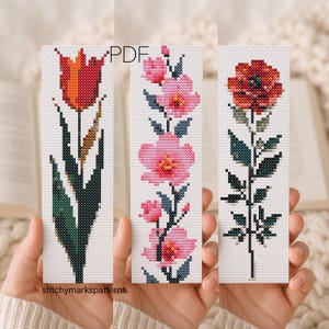Puede incluir: Tres patrones de punto de cruz rectangulares sobre tela blanca. A la izquierda, un tulipán rojo y naranja con hojas verde oscuro. En el centro, flores rosas en una enredadera. A la derecha, una amapola roja con hojas y tallo verde oscuro.