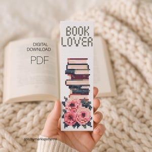 May include: A cross-stitch pattern bookmark featuring the text BOOK LOVER in black, a stack of books in shades of blue, purple, and pink, and a cluster of pink flowers at the bottom. This is a digital download PDF file for a craft project.