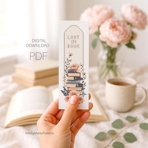 May include: A rectangular cross-stitch bookmark pattern featuring a stack of books, floral accents, and the text LOST IN BOOK. The design is presented as a digital download PDF, showcasing a vertical orientation with a pointed top edge and detailed embroidery motifs in muted tones.
