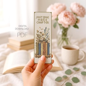 May include: A handmade bookmark with the text "JUST ONE MORE CHAPTER" above a design of books and flowers. The bookmark is held in a hand, with a blurred background of books, flowers, and a cup of tea. The words "DIGITAL DOWNLOAD PDF" are also visible.