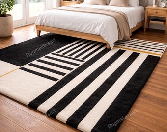 May include: A modern bedroom with a wooden bed frame, white bedding, and two bedside tables. The focal point is a large area rug with a geometric design in black and white stripes and blocks. The rug is placed on a hardwood floor.