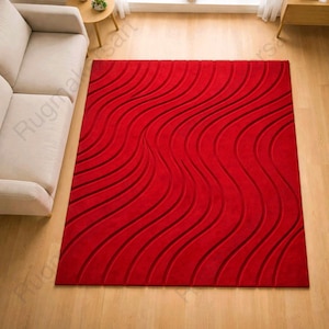 May include: A bright red rectangular rug with a wave design. The rug has a series of raised, flowing lines that create a textured effect. The rug appears to be made of a soft material, adding warmth to the room. The rug is approximately 200 cm x 300 cm.