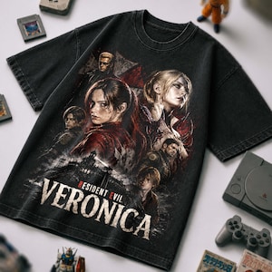 Può includere: Una t-shirt nera a maniche corte con una stampa grafica di diversi personaggi della serie Resident Evil. Il testo "RESIDENT EVIL VERONICA" è stampato in grandi lettere bianche nella parte inferiore, con accenti rossi sulla parola "EVIL".