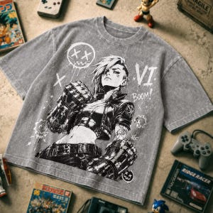 May include: A grey acid-wash t-shirt featuring a black and white graphic print of a character with short hair wearing large mechanical gauntlets. The design includes the text VI and BOOM, along with stylised circular icons and cross symbols.