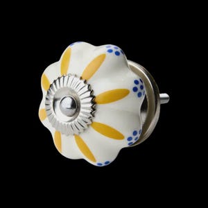 May include: A ceramic cabinet knob with a white base, featuring yellow petal patterns and blue polka dots. The knob has a silver metal base and centre. Ideal for adding colour to furniture. The knob's dimensions are approximately 4 cm in diameter.