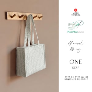 Könnte beinhalten: Eine hellgraue, gesteppte Tragetasche mit zwei Schulterriemen, die an einer hölzernen Wandgarderobe mit vier Haken hängt. Der Text rechts lautet: VIDEO TUTORIAL, PixelMintStudio, Guest Bag, ONE SIZE, STEP BY STEP GUIDE BEGINNER FRIENDLY.