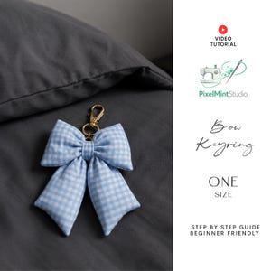 May include: A light blue and white gingham fabric bow keyring with a gold-tone metal lobster clasp. The image includes text reading Video Tutorial, PixelMintStudio, Bow Keyring, One Size, and Step By Step Guide Beginner Friendly.